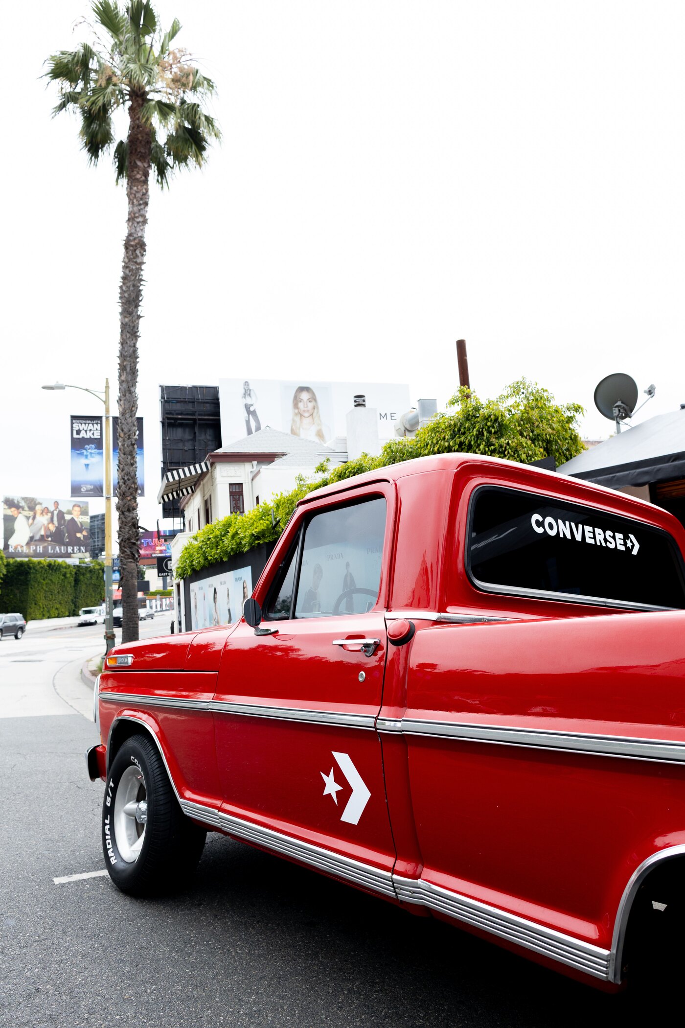 The red 1972 Ford F-100 parked on Sunset Boulevard wearing Converse decals on the door and rear window during a street activation.
